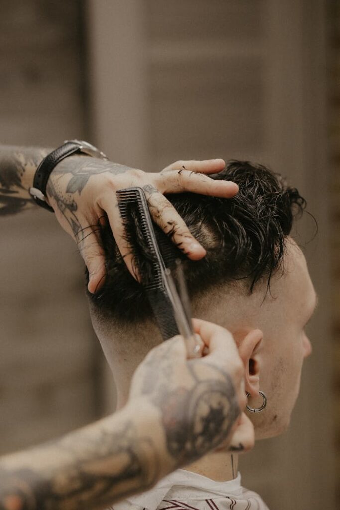 Mastering the First Impression: Your intriguing post title goes here A barber with tattoos trims a man's hair with precision in a Belarusian barber shop.